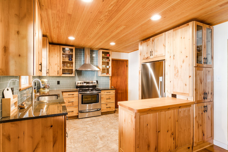 This is an example of a mid-sized transitional l-shaped eat-in kitchen in Richmond with flat-panel cabinets, light wood cabinets, granite benchtops, glass tile splashback, a peninsula and wood.