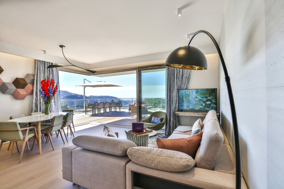 Großes, Offenes Modernes Wohnzimmer mit blauer Wandfarbe, braunem Holzboden, freistehendem TV, braunem Boden und Tapetenwänden in Nizza