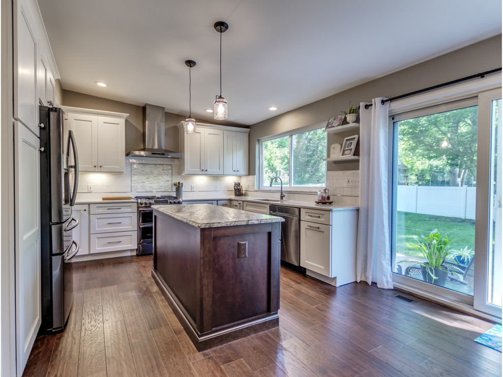 Inspiration for a mid-sized transitional u-shaped brown floor eat-in kitchen remodel in St Louis with white cabinets, white backsplash, subway tile backsplash, stainless steel appliances, an island, granite countertops and multicolored countertops