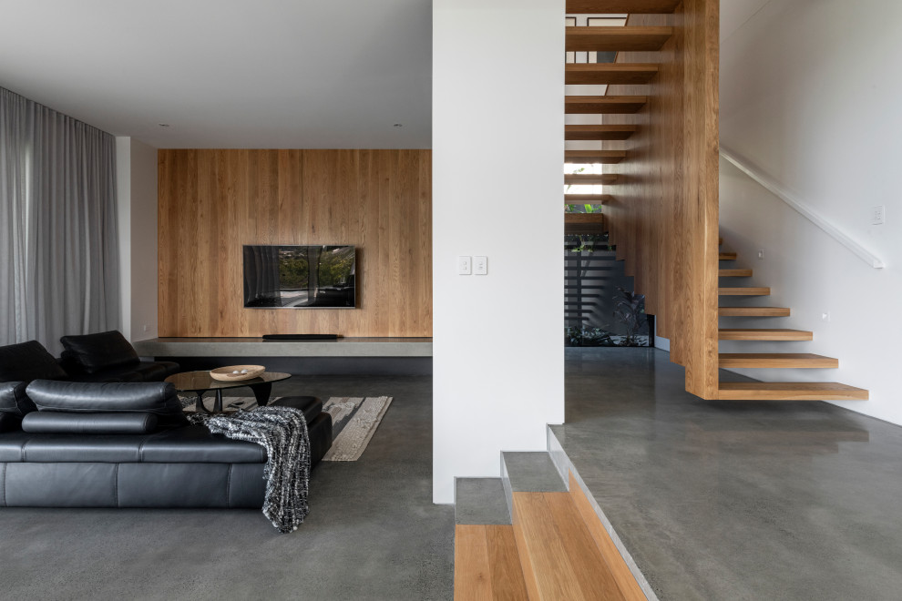 Modern open concept living room in Brisbane with white walls, concrete floors, a wall-mounted tv, grey floor and wood walls.