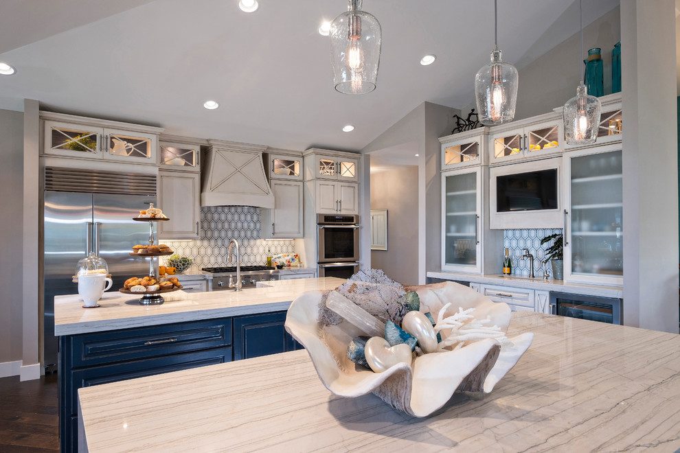 This is an example of a mid-sized beach style u-shaped open plan kitchen in Miami with a farmhouse sink, raised-panel cabinets, beige cabinets, marble benchtops, stainless steel appliances and multiple islands.