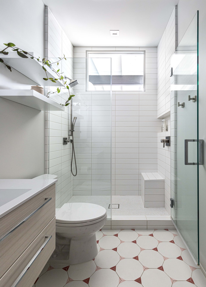 This is an example of a mid-sized midcentury 3/4 bathroom in Sacramento with flat-panel cabinets, white cabinets, a one-piece toilet, white tile, ceramic tile, grey walls, ceramic floors, laminate benchtops, pink floor, a hinged shower door, white benchtops, a shower seat, a single vanity, a floating vanity and exposed beam.