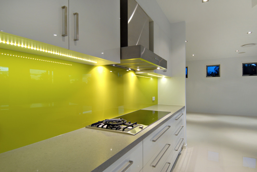 This is an example of a large modern galley kitchen pantry in Brisbane with a double-bowl sink, yellow splashback, porcelain splashback, stainless steel appliances, porcelain floors and no island.