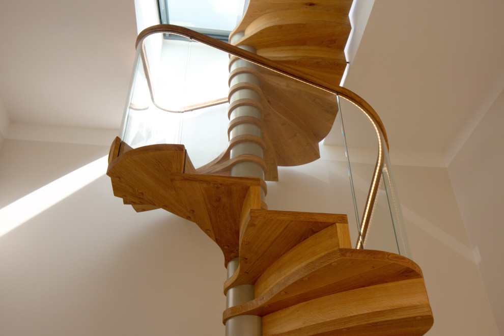 Diseño de escalera de caracol contemporánea grande con escalones de madera, contrahuellas de madera, barandilla de vidrio y papel pintado