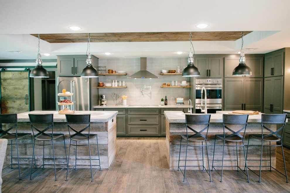 This is an example of a transitional kitchen in Austin with shaker cabinets, grey splashback, stainless steel appliances, medium hardwood floors and multiple islands.