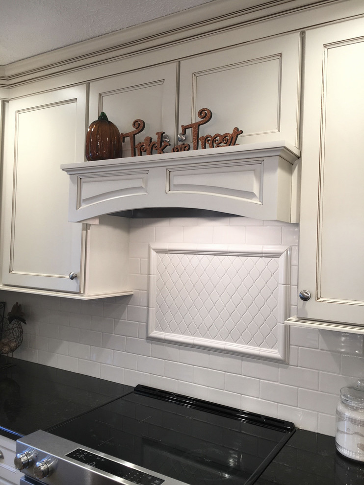 Large transitional medium tone wood floor and brown floor eat-in kitchen photo with an undermount sink, flat-panel cabinets, white cabinets, granite countertops, white backsplash, porcelain backsplash, stainless steel appliances and an island