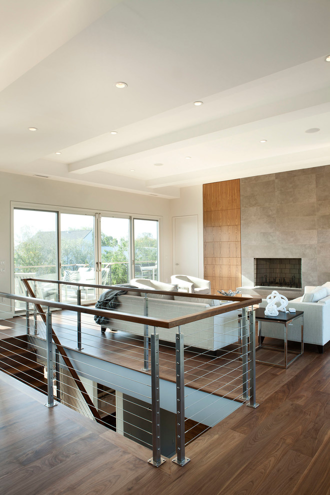 Photo of a mid-sized modern formal loft-style living room with grey walls, medium hardwood floors, a standard fireplace, a tile fireplace surround, no tv and brown floor.