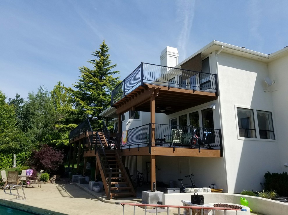 Example of a huge transitional backyard deck design with a fire pit and a roof extension