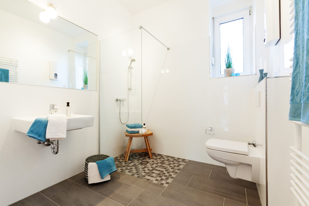 Design ideas for a small scandinavian 3/4 bathroom in Essen with a corner shower, a wall-mount toilet, gray tile, white tile, white walls and a wall-mount sink.
