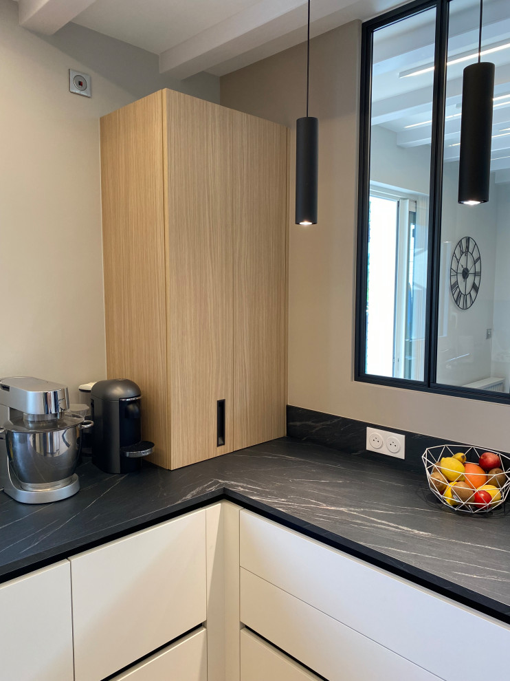 This is an example of a medium sized contemporary u-shaped open plan kitchen in Nantes with black splashback and black worktops.