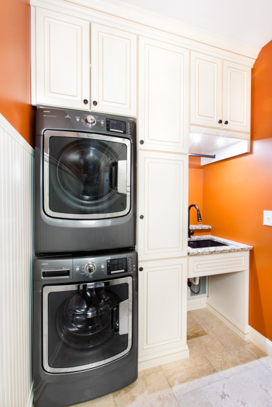 Inspiration for a small traditional laundry room in Chicago with an undermount sink, raised-panel cabinets, white cabinets, granite benchtops, orange walls, ceramic floors and a stacked washer and dryer.