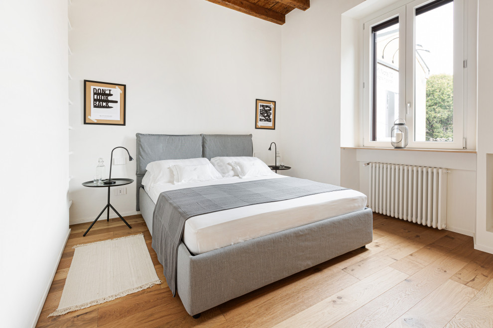 Small scandi master bedroom in Milan with white walls, light hardwood flooring, no fireplace, brown floors, a wood ceiling and all types of wall treatment.