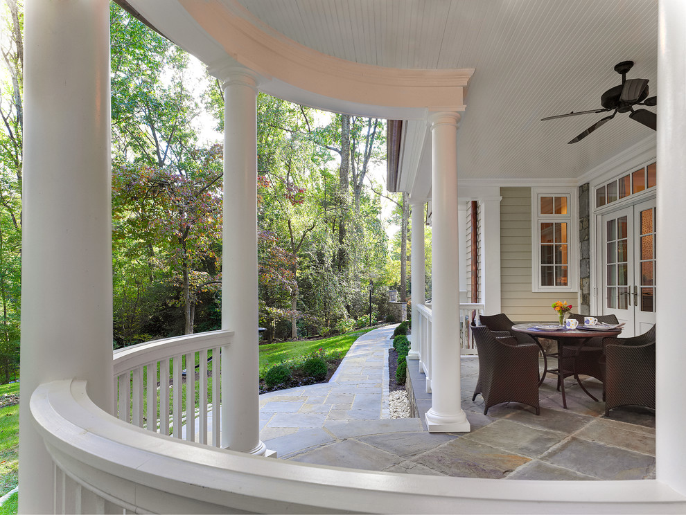 Inspiration for a traditional verandah in DC Metro with natural stone pavers and a roof extension.