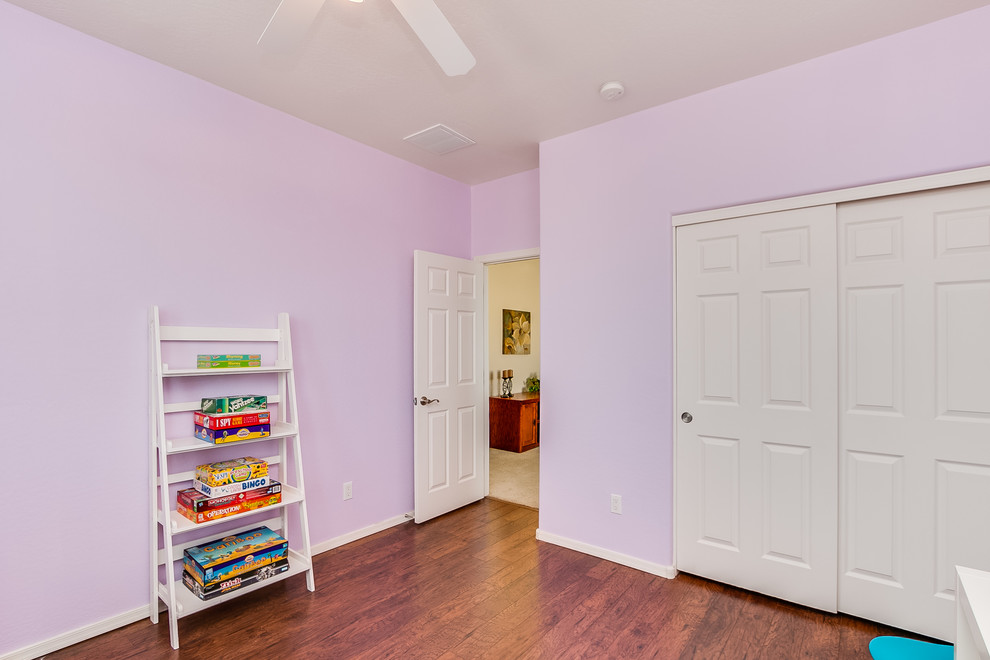 This is an example of a mid-sized traditional kids' playroom for kids 4-10 years old and girls in Phoenix with pink walls, dark hardwood floors and brown floor.
