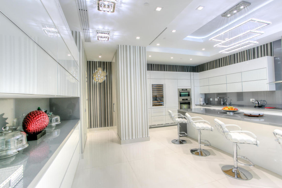 This is an example of an expansive contemporary l-shaped eat-in kitchen in Miami with an undermount sink, flat-panel cabinets, white cabinets, stainless steel benchtops, metallic splashback, metal splashback, stainless steel appliances, porcelain floors and with island.