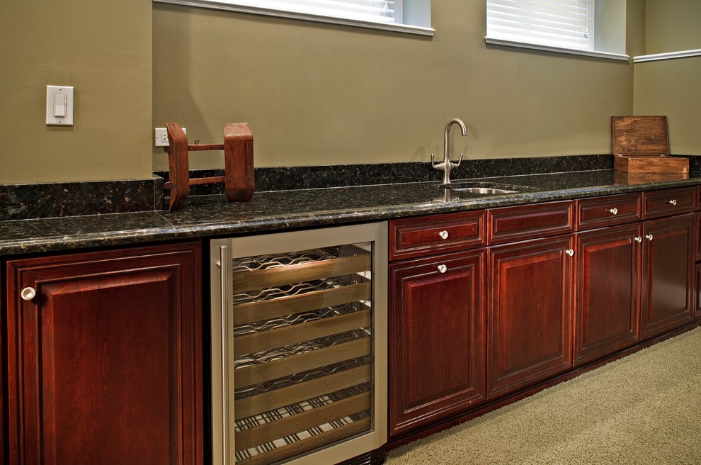 Photo of a large traditional single-wall wet bar in Chicago with an undermount sink, raised-panel cabinets, red cabinets, granite benchtops and beige splashback.
