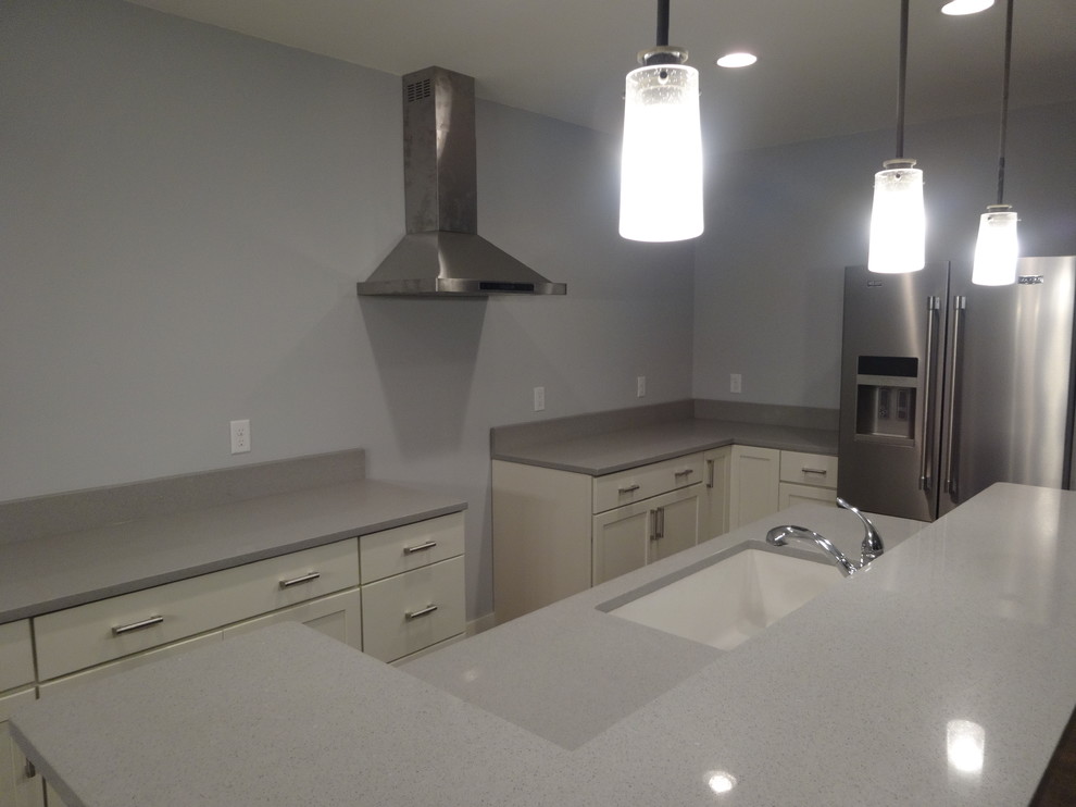 Inspiration for a mid-sized transitional l-shaped porcelain tile eat-in kitchen remodel in Milwaukee with a single-bowl sink, recessed-panel cabinets, white cabinets, quartz countertops, gray backsplash, stone slab backsplash, stainless steel appliances and an island