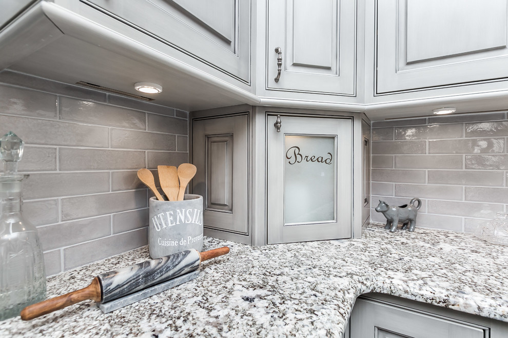 This is an example of a large traditional u-shaped eat-in kitchen in Baltimore with a farmhouse sink, beaded inset cabinets, grey cabinets, granite benchtops, grey splashback, white appliances, medium hardwood floors, with island and grey floor.