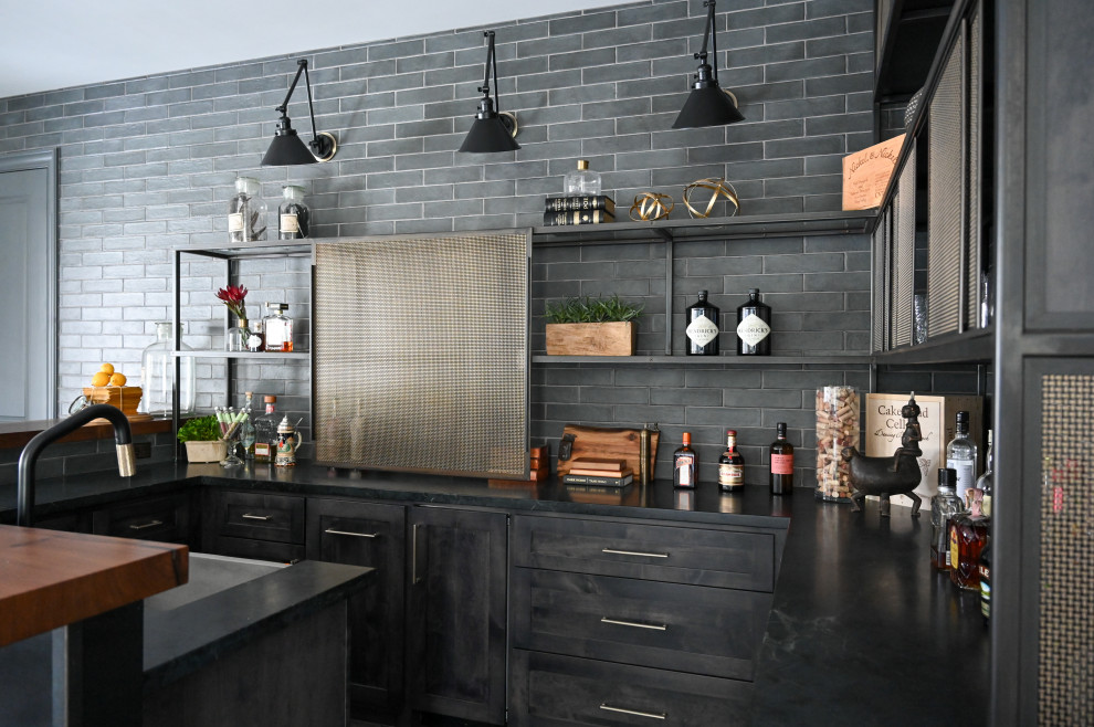 Photo of a large industrial l-shaped seated home bar in Houston with a drop-in sink, open cabinets, grey cabinets, wood benchtops, grey splashback, subway tile splashback, ceramic floors, multi-coloured floor and brown benchtop.