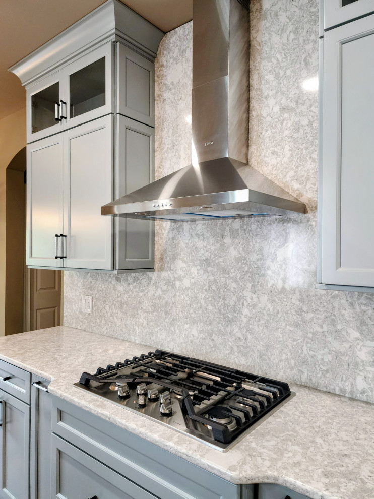 Inspiration for a mid-sized transitional medium tone wood floor and brown floor open concept kitchen remodel with an undermount sink, shaker cabinets, quartz countertops, white backsplash, quartz backsplash, stainless steel appliances, an island and white countertops