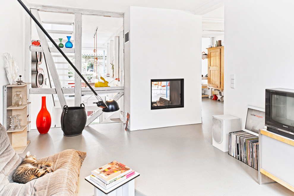 Photo of a mid-sized contemporary open concept living room in Stuttgart with white walls, linoleum floors, a two-sided fireplace, a plaster fireplace surround and a freestanding tv.