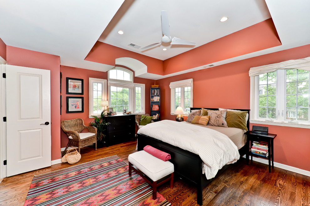 This is an example of a transitional master bedroom in DC Metro with orange walls and dark hardwood floors.