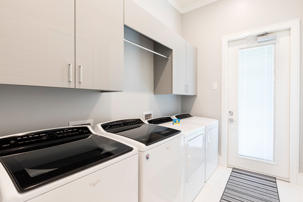 This is an example of a large modern single-wall separated utility room in Orlando with flat-panel cabinets, grey cabinets, grey walls, porcelain flooring, a side by side washer and dryer and white floors.