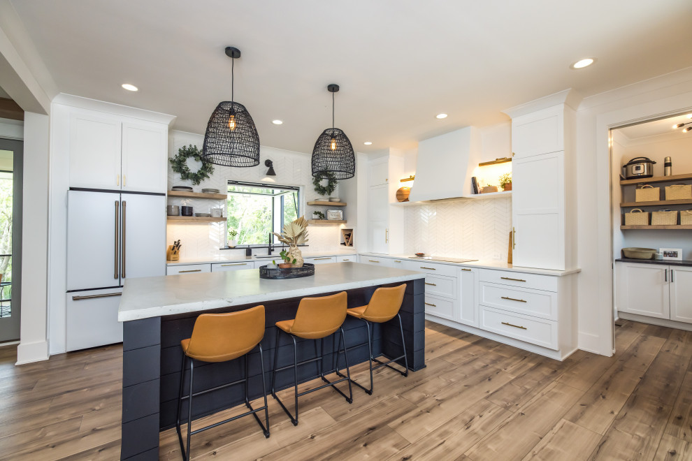 Modern kitchen in Wilmington with recessed-panel cabinets, white cabinets, white splashback, glass tile splashback, white appliances, medium hardwood floors, with island, brown floor and white benchtop.
