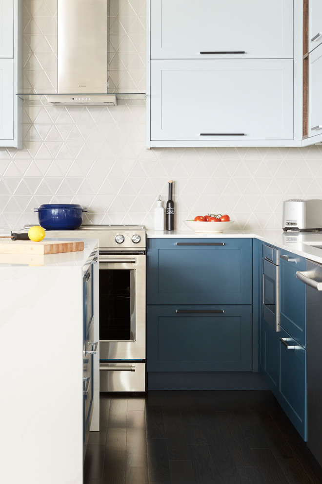 Photo of a mid-sized modern l-shaped eat-in kitchen in Toronto with a single-bowl sink, shaker cabinets, blue cabinets, quartz benchtops, beige splashback, ceramic splashback, stainless steel appliances, dark hardwood floors, with island, brown floor and white benchtop.