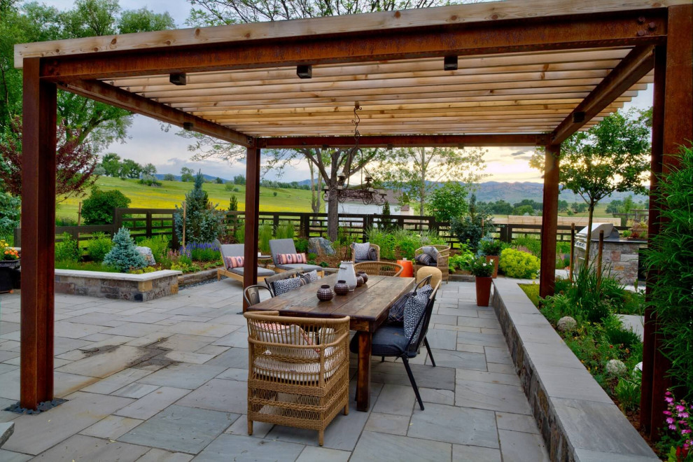 Design ideas for a large country backyard partial sun garden for summer in Denver with natural stone pavers and a metal fence.