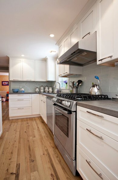 Example of a mid-sized transitional light wood floor eat-in kitchen design in Houston with a drop-in sink, recessed-panel cabinets, white cabinets, blue backsplash, glass tile backsplash, stainless steel appliances, gray walls and an island