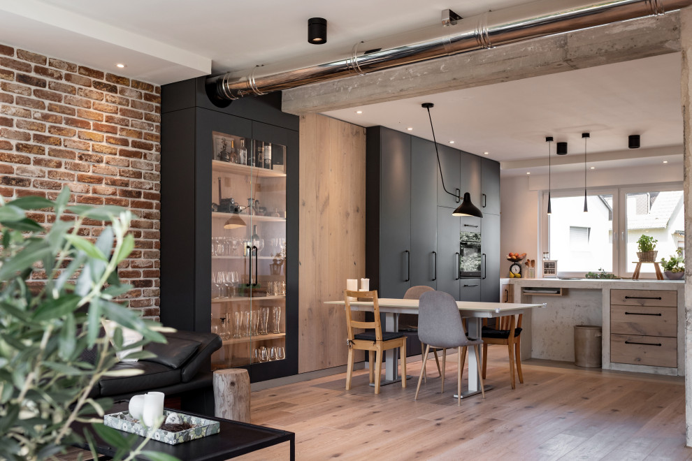 Inspiration pour une salle à manger ouverte sur la cuisine urbaine de taille moyenne avec un mur noir, un sol en bois brun, un sol beige et un mur en parement de brique.