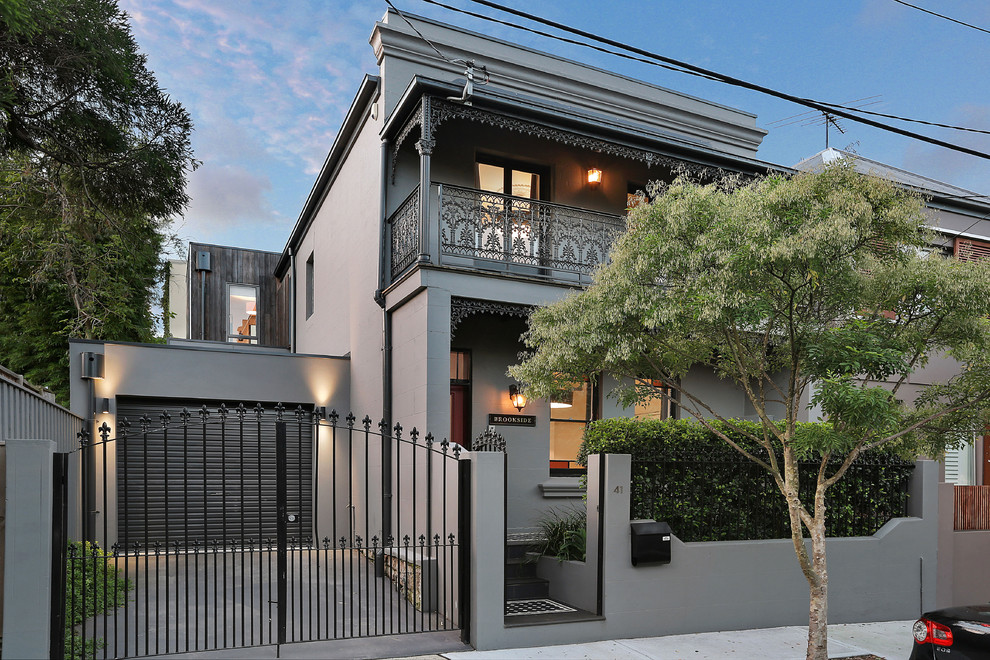 Photo of a large transitional two-storey stucco grey townhouse exterior in Sydney with a flat roof.