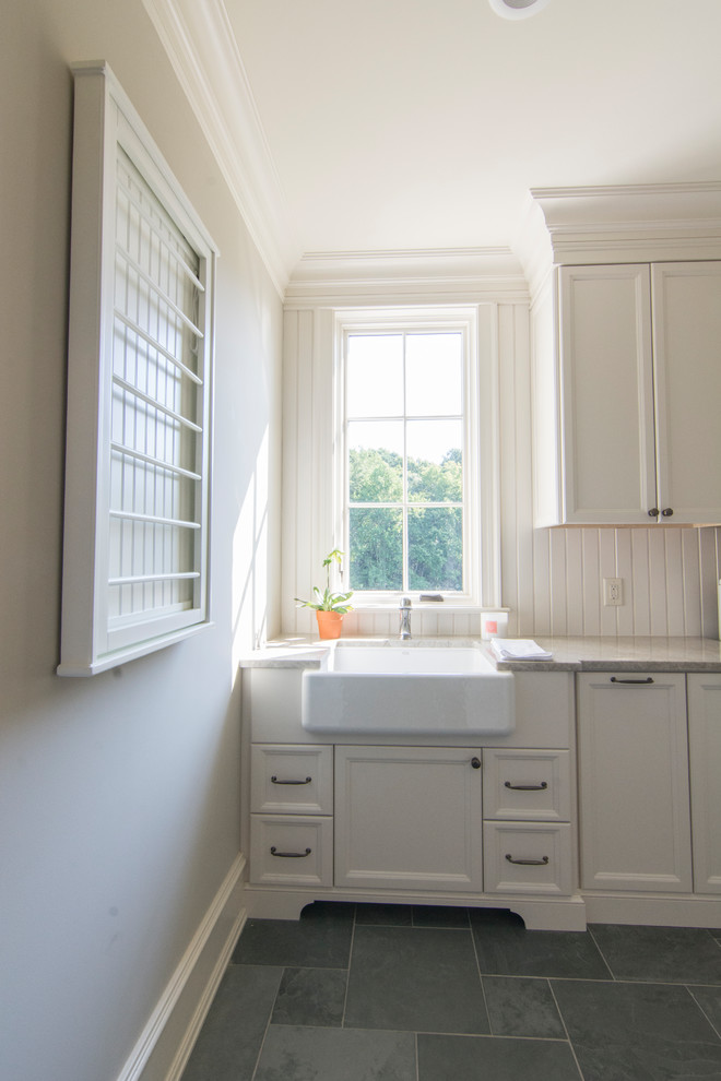 This is an example of a large eclectic utility room in Raleigh with a farmhouse sink, white cabinets, wood benchtops, grey walls, slate floors, a side-by-side washer and dryer and recessed-panel cabinets.