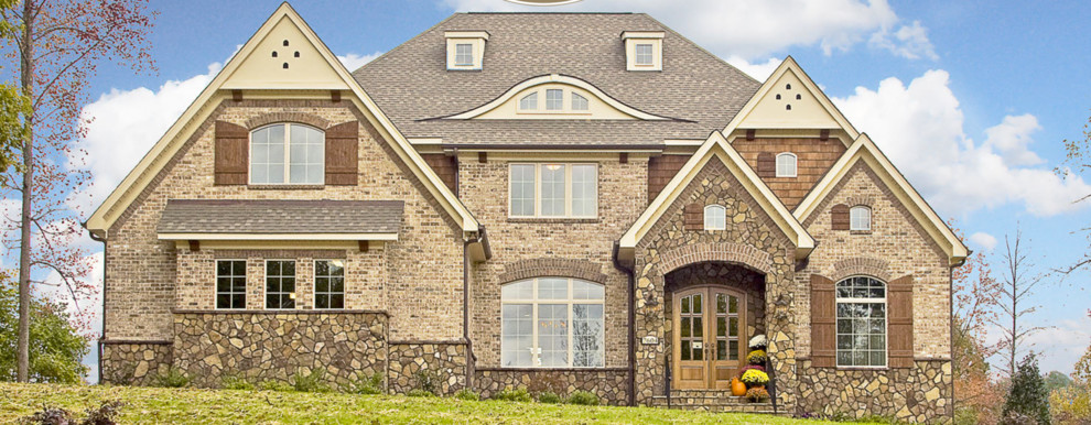 Large transitional two-storey brick beige house exterior in Other with a gable roof and a shingle roof.