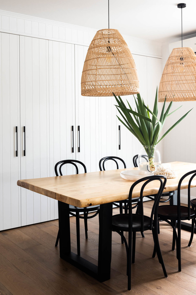 This is an example of a beach style dining room in Brisbane with white walls, medium hardwood floors and brown floor.