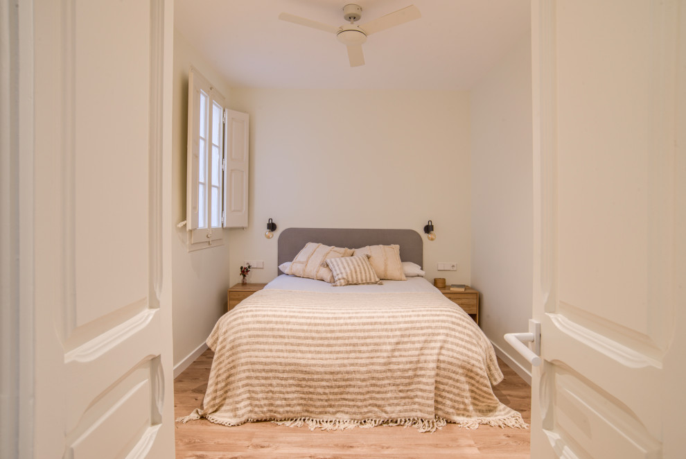 Imagen de dormitorio principal y blanco y madera escandinavo pequeño con paredes blancas, suelo laminado y suelo marrón