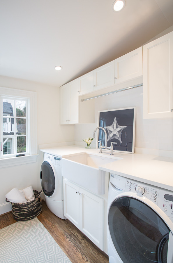 Mid-sized traditional single-wall dedicated laundry room in DC Metro with a farmhouse sink, recessed-panel cabinets, white cabinets, dark hardwood floors and a side-by-side washer and dryer.