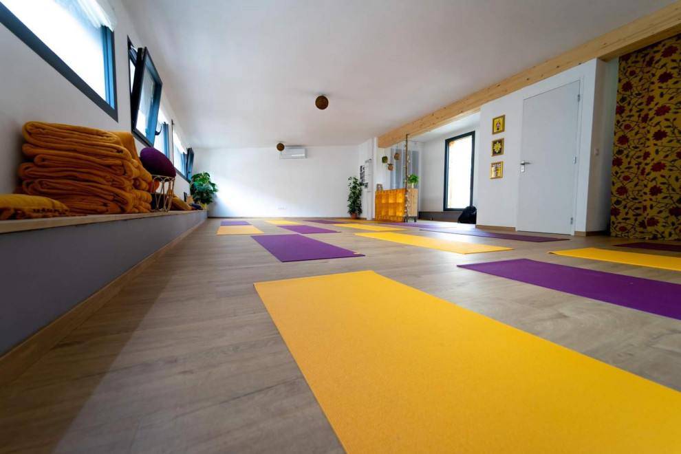 Ispirazione per uno studio yoga tropicale di medie dimensioni con pareti bianche, parquet chiaro e pavimento marrone