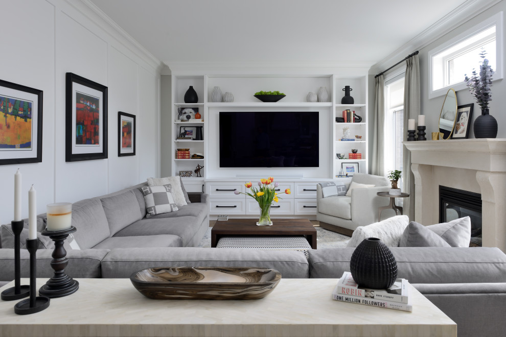 This is an example of a large transitional living room in Toronto with white walls, medium hardwood floors, a standard fireplace, a concrete fireplace surround, a built-in media wall, brown floor and panelled walls.