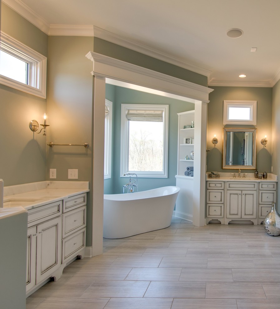 Photo of a mid-sized traditional bathroom in Nashville with beaded inset cabinets, white cabinets, a freestanding tub, green walls, porcelain floors, an undermount sink and engineered quartz benchtops.