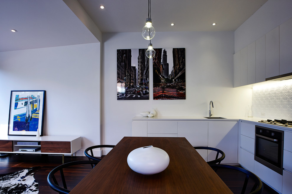 Photo of a small contemporary l-shaped eat-in kitchen in Melbourne with an undermount sink, flat-panel cabinets, white cabinets, quartzite benchtops, white splashback, metal splashback, stainless steel appliances and dark hardwood floors.