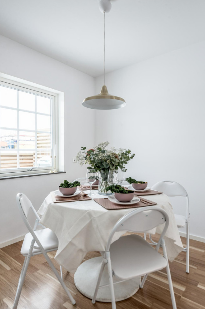 Inspiration for a scandinavian kitchen/dining combo in Other with white walls, laminate floors and brown floor.