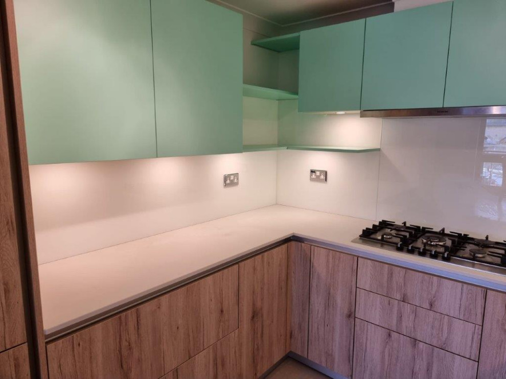 Modelo de cocinas en L actual pequeña cerrada con armarios con paneles lisos, puertas de armario verdes y salpicadero blanco
