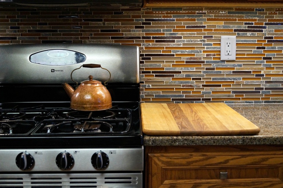 Inspiration for a transitional open concept kitchen remodel in Cedar Rapids with recessed-panel cabinets, medium tone wood cabinets, quartz countertops, glass sheet backsplash, stainless steel appliances, an island and multicolored backsplash