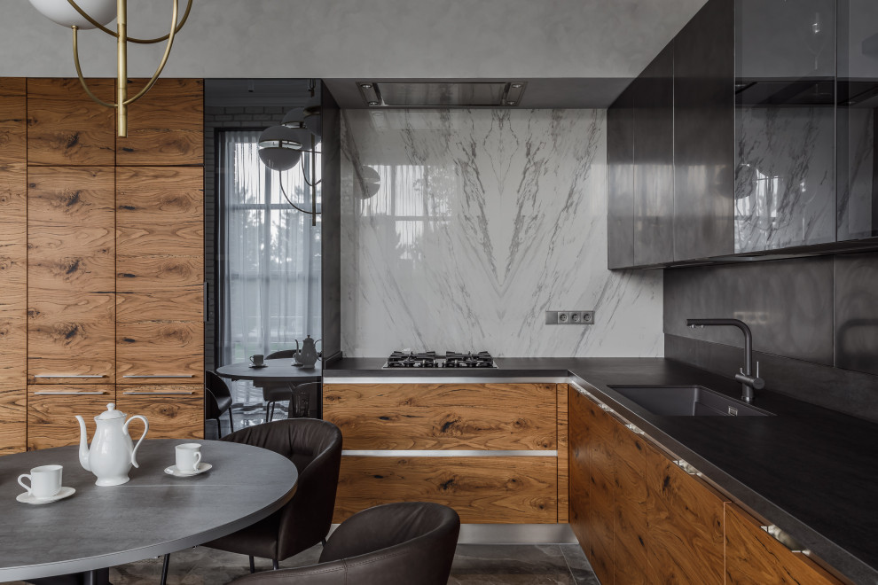 Immagine di una cucina contemporanea con ante di vetro, ante in legno scuro, paraspruzzi grigio, elettrodomestici neri e top grigio