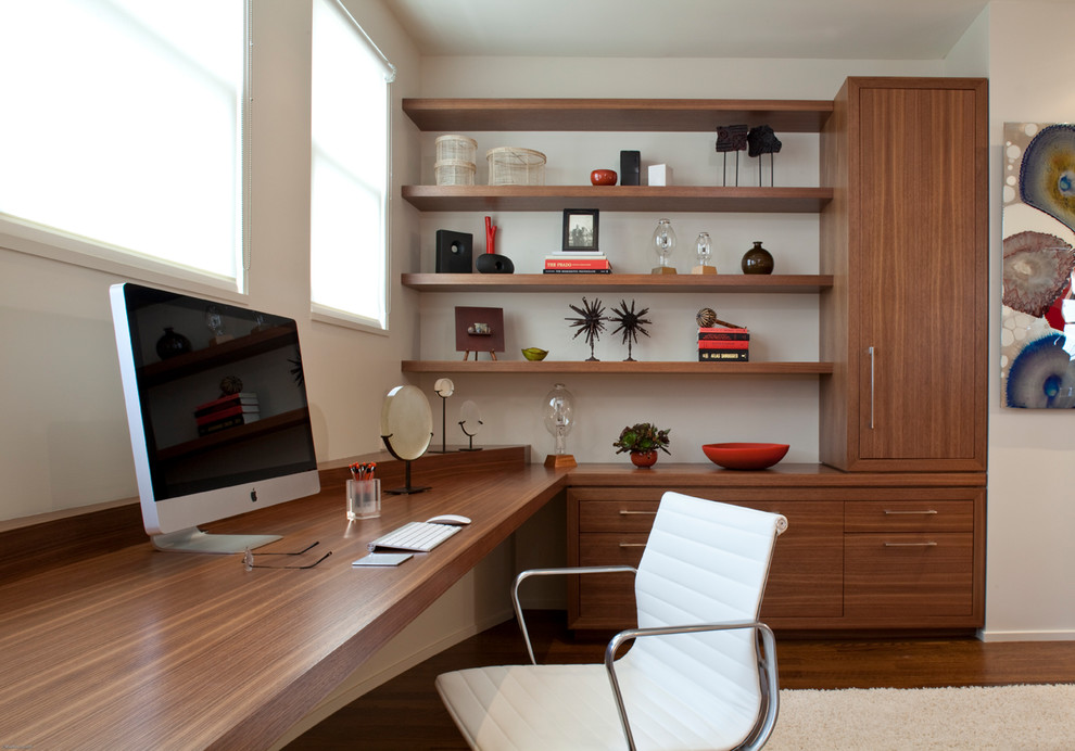 Photo of a mid-sized modern home office in San Francisco with beige walls, dark hardwood floors, a built-in desk and brown floor.