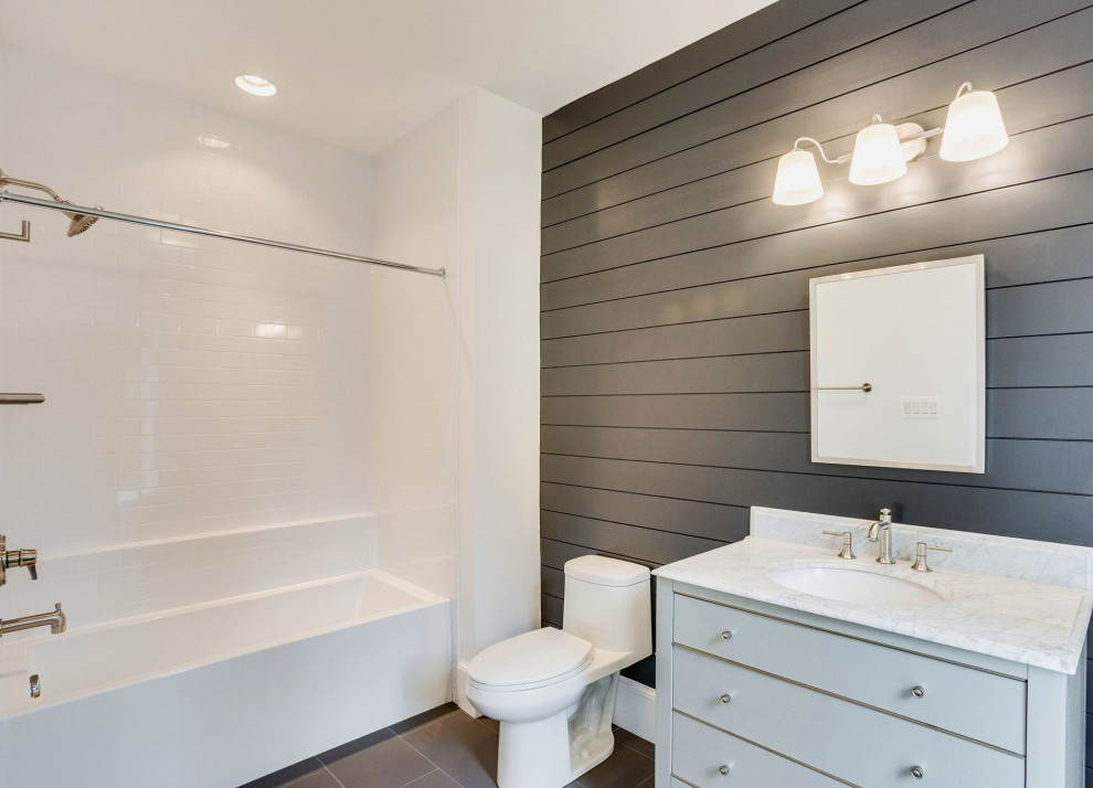 Transitional kids bathroom in DC Metro with furniture-like cabinets, grey cabinets, an alcove tub, a two-piece toilet, white tile, subway tile, grey walls, porcelain floors, an undermount sink, marble benchtops, grey floor, white benchtops, a shower seat, a single vanity, a freestanding vanity and planked wall panelling.