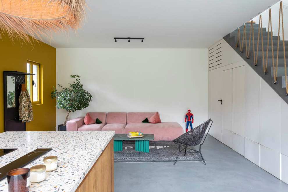 Foto på ett mellanstort allrum med öppen planlösning, med vita väggar, betonggolv, en dold TV och grått golv