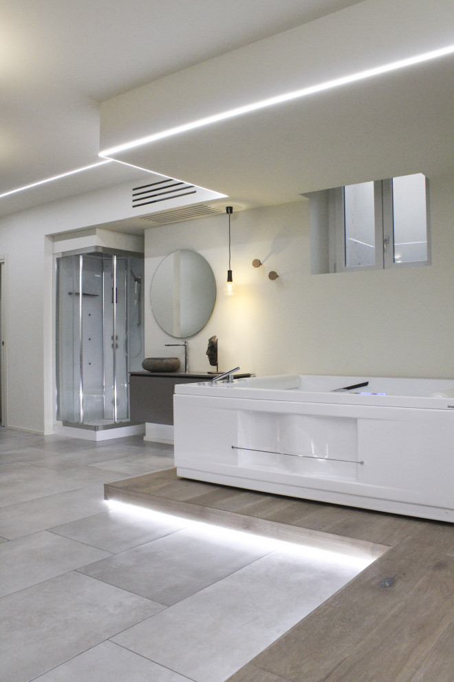 Aménagement d'une salle de bain moderne de taille moyenne avec des portes de placard grises, un bain bouillonnant, une douche d'angle, un mur blanc, sol en béton ciré, une vasque, un sol gris, une cabine de douche à porte battante, meuble simple vasque et meuble-lavabo sur pied.